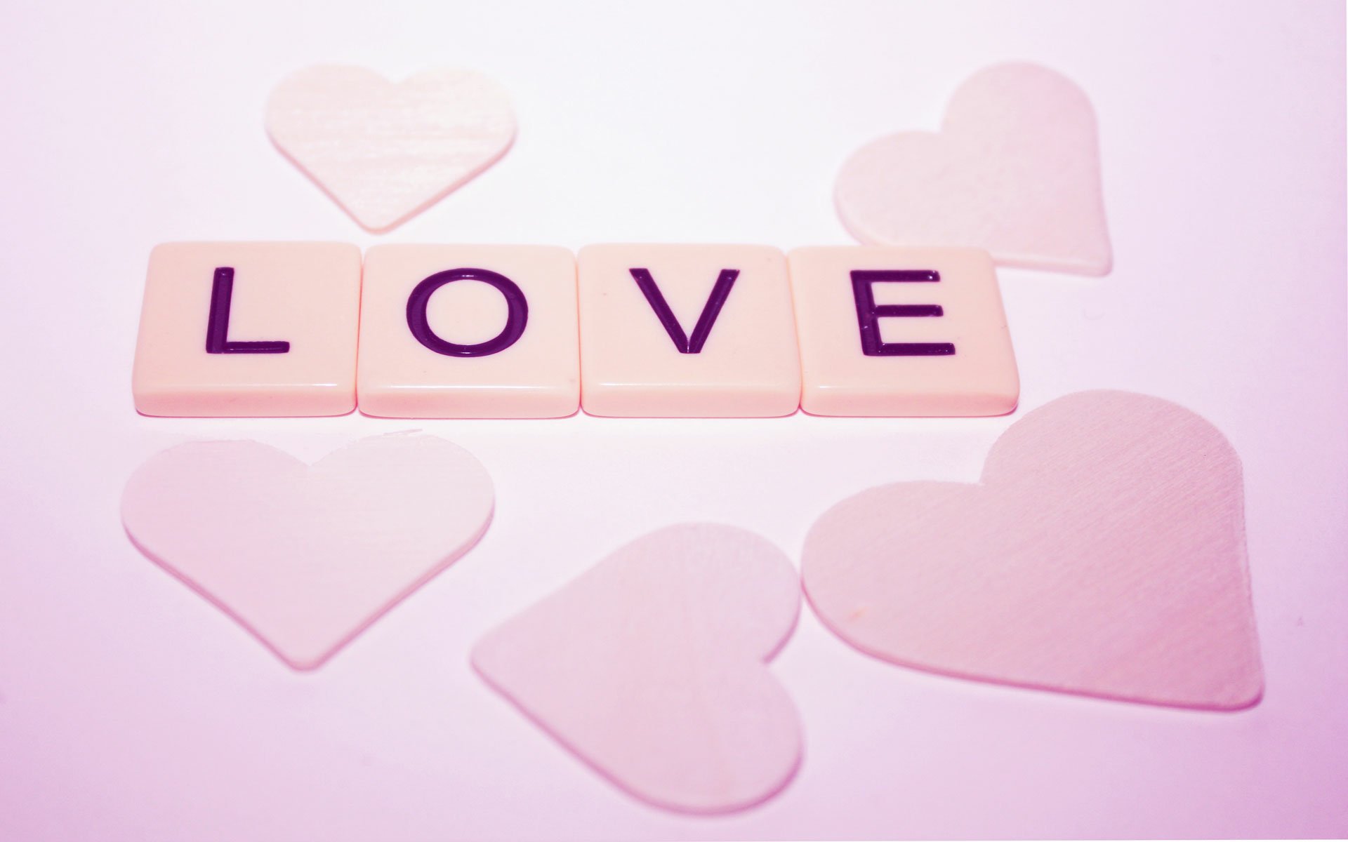 Artistic HD wallpaper featuring the word LOVE in bold tiles, surrounded by soft, heart-shaped accents, creating a warm and inviting background.