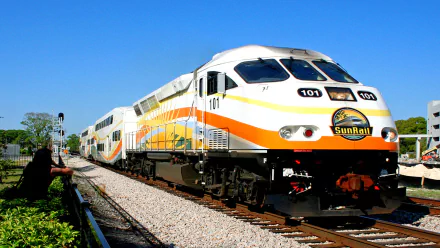 HD desktop wallpaper featuring a sleek SunRail passenger train traveling on tracks under a clear blue sky.
