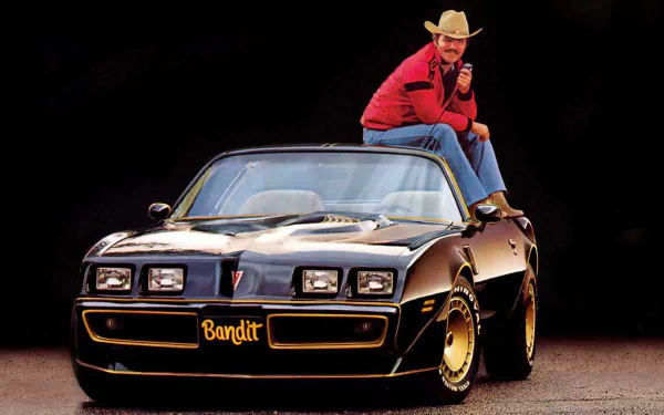 HD PC desktop wallpaper featuring the movie Smokey and the Bandit with the Bandit character sitting on a black Trans Am car against a dark background.