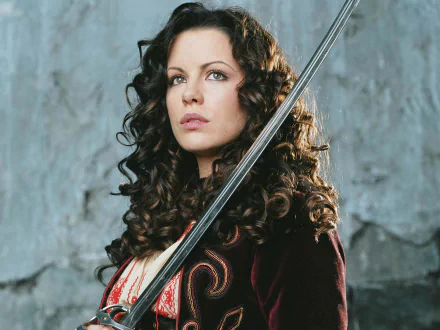 A striking HD wallpaper featuring Kate Beckinsale as she appears in Van Helsing, showcasing her fierce expression and elegant attire, sword in hand against a textured backdrop.