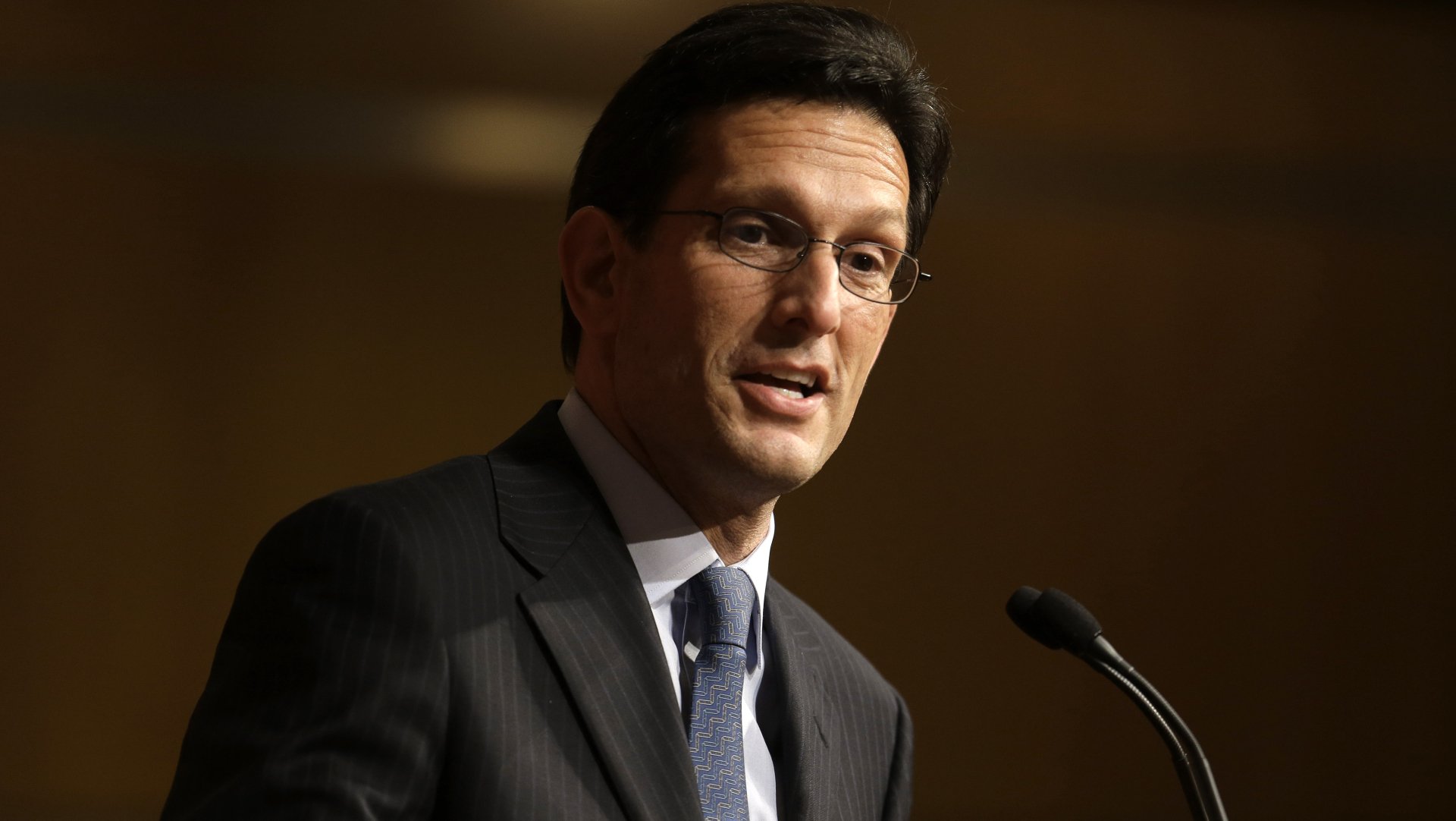 HD desktop wallpaper featuring a man in a suit at a podium, used as a background image.