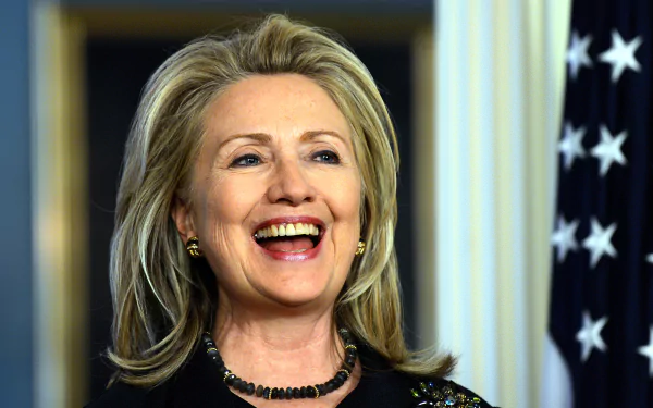 HD wallpaper featuring a smiling woman with blonde hair in front of an American flag, serving as a desktop background.