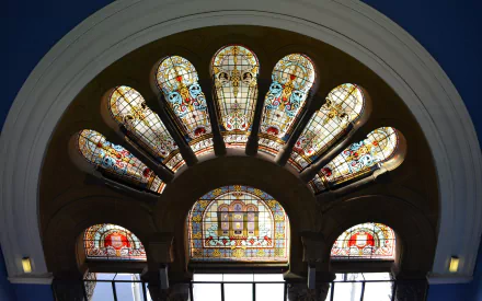 Colorful stained glass archway at the Queen Victoria Building in Sydney, showcasing intricate man-made window designs in a vibrant HD desktop wallpaper background.