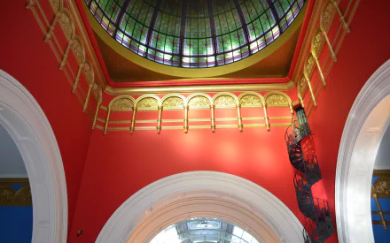 Interior architecture photograph of the Queen Victoria Building dome with stained-glass skylight, ornate arches, red walls and a wrought-iron spiral staircase — HD PC desktop wallpaper
