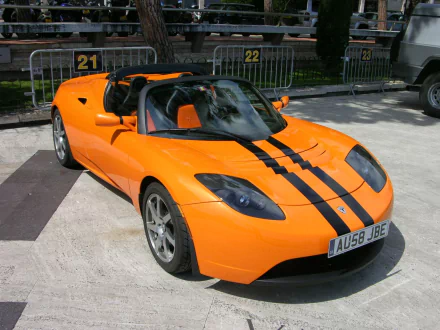 HD wallpaper of an orange Tesla Roadster with black stripes, parked outdoors.