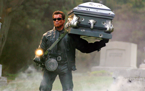Arnold Schwarzenegger as the Terminator carrying a coffin in a dramatic scene from Terminator 3: Rise of the Machines, featured as an HD PC desktop wallpaper.