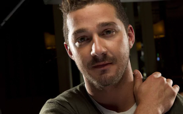 HD desktop wallpaper featuring a close-up of Shia LaBeouf with a subtle smile in a dimly lit setting.