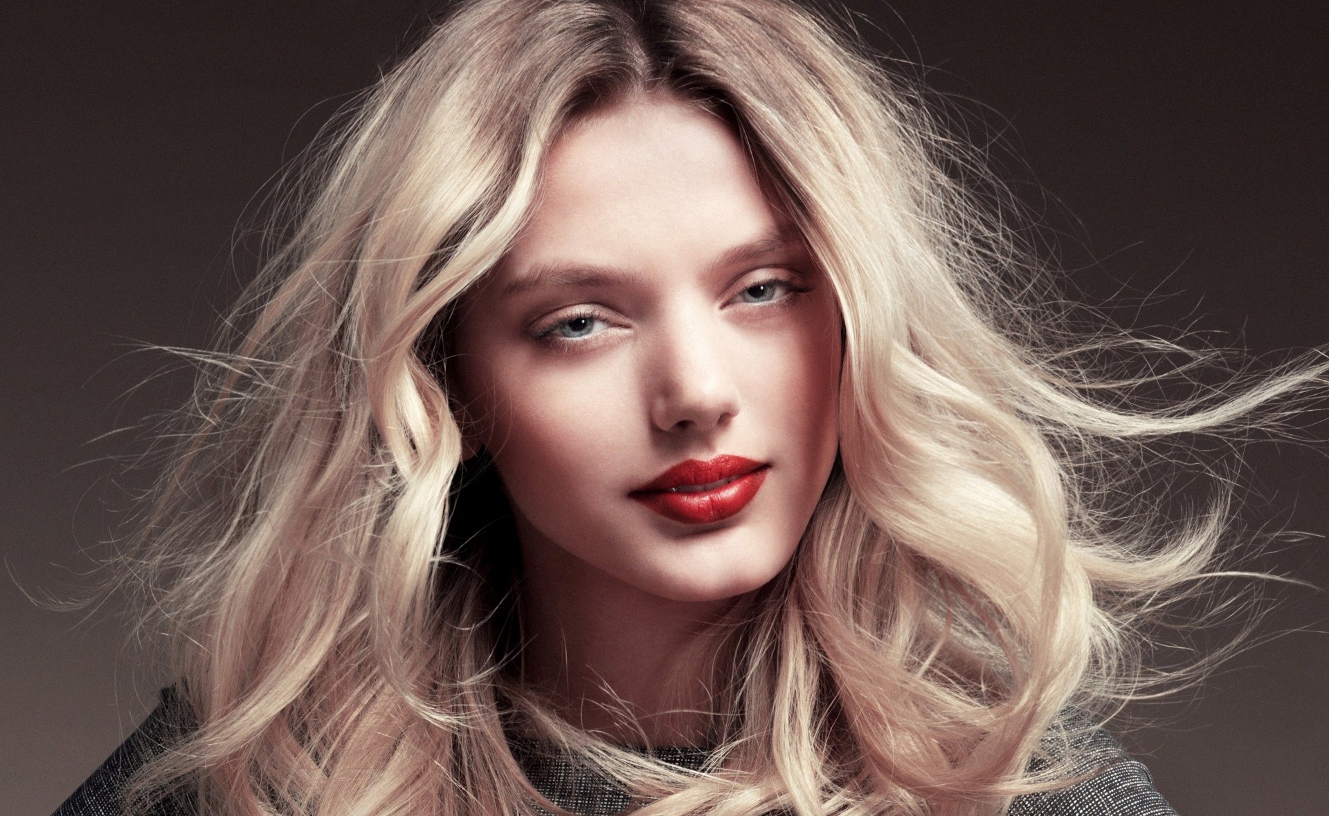 HD PC desktop wallpaper of a Dutch model woman with long wavy blonde hair, red lipstick and soft lighting against a neutral background.