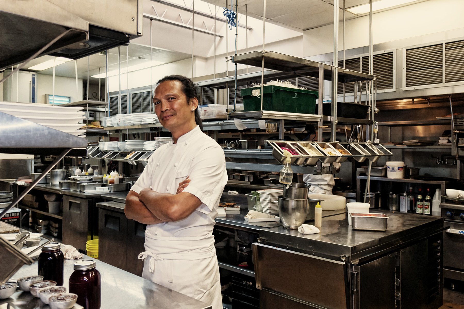 HD desktop wallpaper featuring a confident chef with crossed arms standing in a professional kitchen environment.