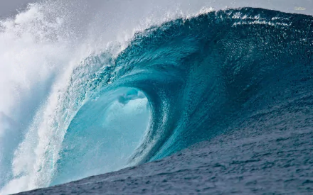 HD desktop wallpaper showcasing a powerful ocean wave curling with vibrant blue and white water, capturing the dynamic beauty of nature.