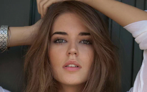 Close-up HD desktop wallpaper of Spanish model Clara Alonso with natural makeup and loose hair, posing with one arm raised behind her head.