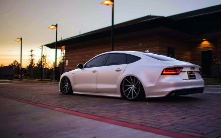 A sleek white Audi A8 parked stylishly at sunset, showcasing its elegant design against a backdrop of warm lighting and modern architecture. A captivating HD desktop wallpaper.
