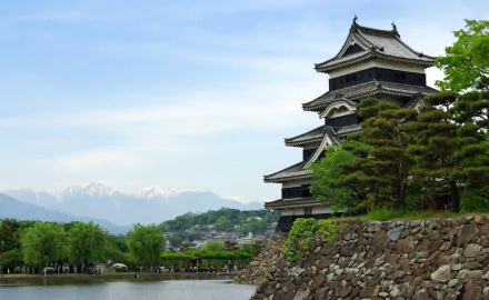 HD desktop wallpaper featuring Matsumoto Castle, a man-made historic structure in Japan, set against a backdrop of mountains and lush greenery.