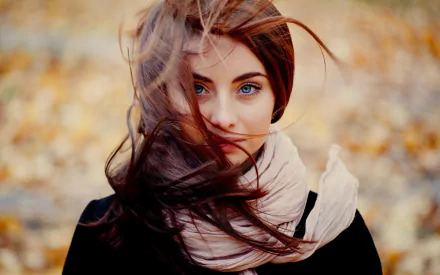 A woman model with flowing hair gazes directly at the viewer, set against a backdrop of autumn leaves, creating a captivating HD desktop wallpaper.