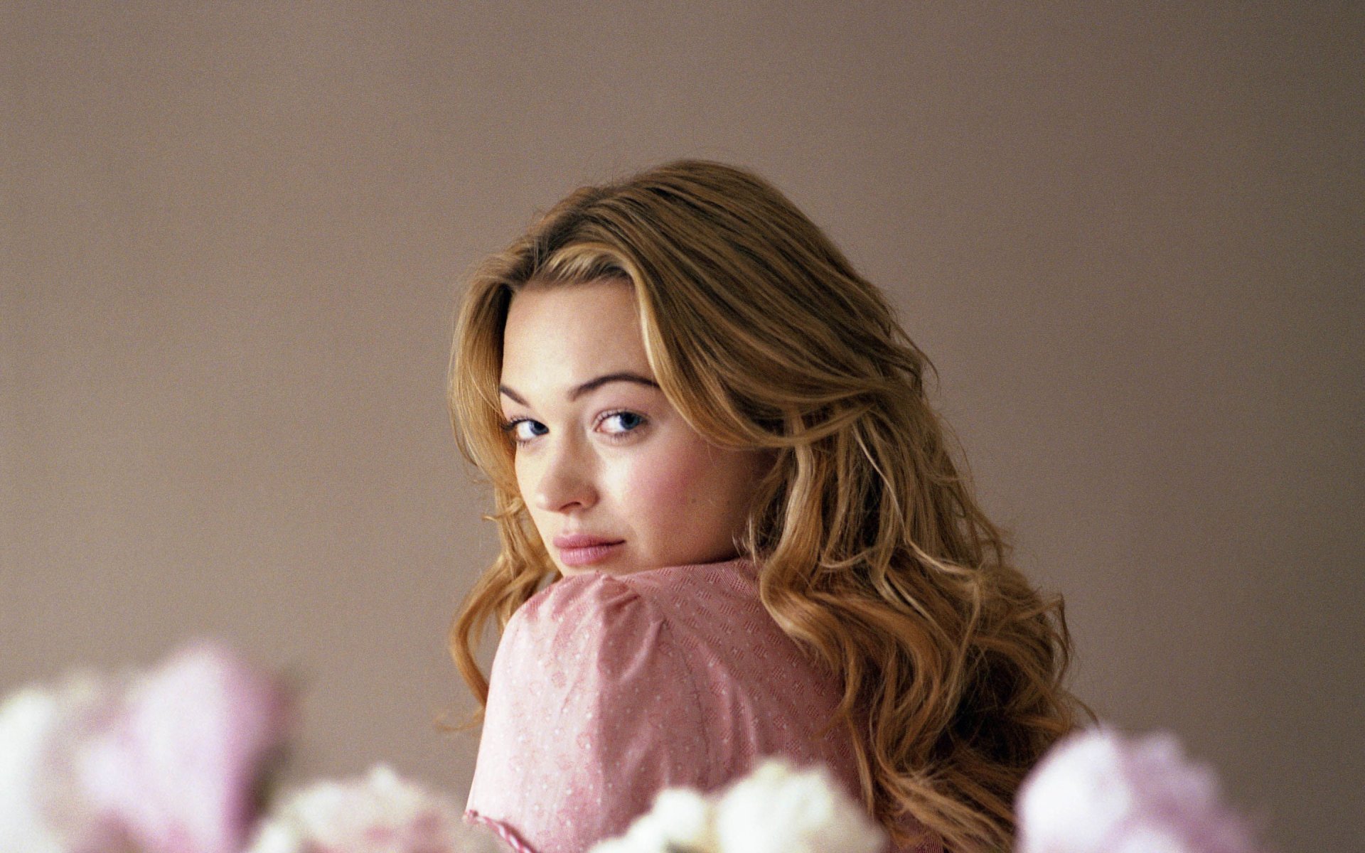 A HD desktop wallpaper featuring actress Sophia Myles, showcasing her looking over her shoulder with soft floral accents in the foreground.