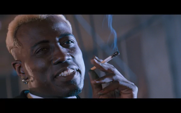 Cinematic close-up of a man with bleached hair and an earring, smoking a cigarette — scene from the movie Demolition Man, presented as an HD PC desktop wallpaper/background.