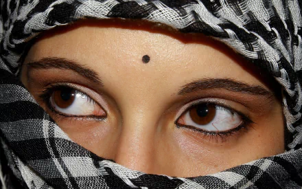 Close-up HD desktop wallpaper of a woman's intense brown eyes, partially covered by a black and white patterned scarf.