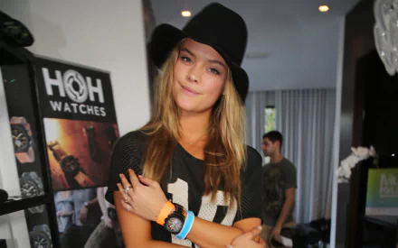 HD desktop wallpaper featuring Danish celebrity model Nina Agdal wearing a black hat and casual outfit, posing indoors with a confident expression.