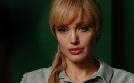 HD PC desktop wallpaper featuring Angelina Jolie from the movie Salt, with her hair in a side braid and a focused expression against a dark green background.