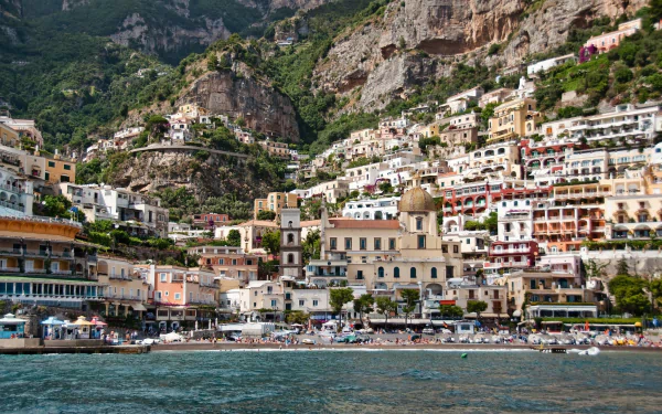 A vibrant view of Positano, Italy, showcasing colorful man-made buildings cascading down cliffs by the sea in Salerno, captured in HD for a desktop wallpaper.