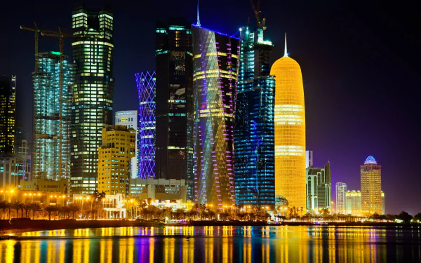 HD desktop wallpaper of Doha's night skyline, featuring illuminated modern skyscrapers reflecting on the water.