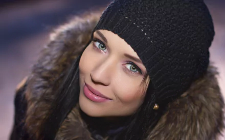 A high-definition desktop wallpaper featuring a woman, identified as Angelina Petrova, wearing a black knit hat and a fur-collared coat, looking directly at the camera with a soft smile.