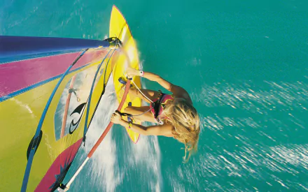 HD desktop wallpaper featuring a dynamic windsurfing scene with a person gliding over turquoise water, showcasing the thrill of the sport.