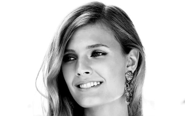 Black-and-white HD desktop wallpaper featuring French model Constance Jablonski smiling with elegant earrings against a white background.