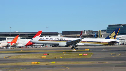A Boeing 777 from Singapore Airlines is landing at Sydney Airport, showcasing the vibrant aviation scene with other aircraft in the background. HD wallpaper for aviation enthusiasts.
