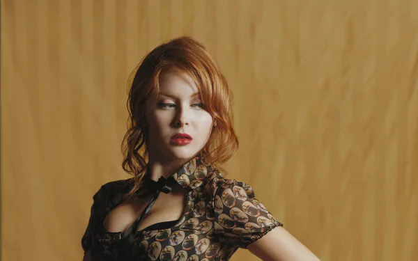 HD desktop wallpaper featuring American actress Renee Olstead with red hair, wearing a patterned blouse against a warm, solid background.