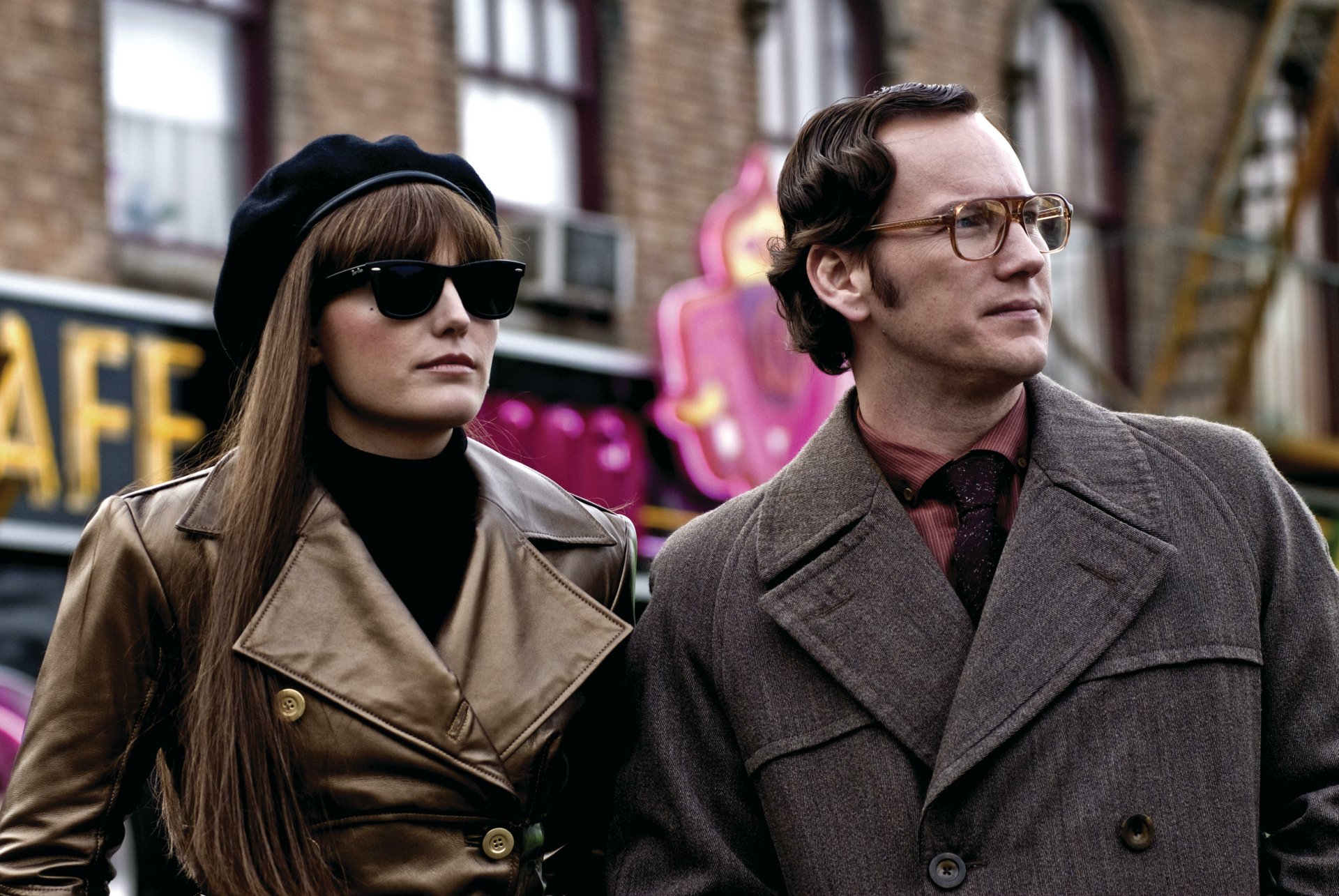 Watchmen movie still: woman in sunglasses and beret beside a man in an overcoat and glasses on a city street — 4K Ultra HD PC desktop wallpaper