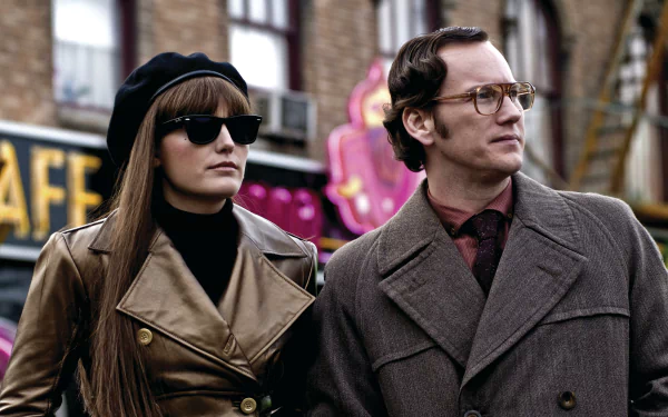 Watchmen movie still: woman in sunglasses and beret beside a man in an overcoat and glasses on a city street — 4K Ultra HD PC desktop wallpaper