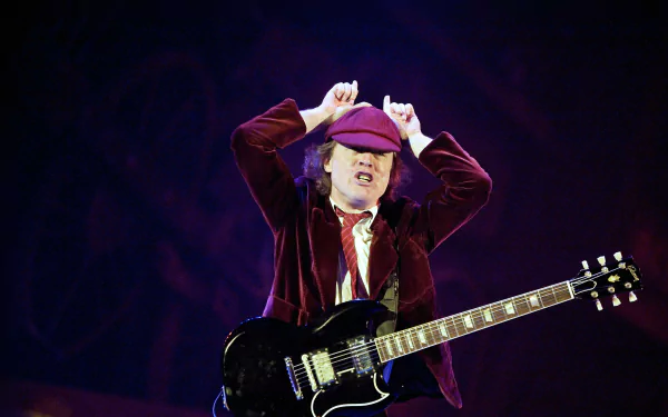 High-resolution 4K Ultra HD PC wallpaper featuring a dynamic live performance of AC/DC’s guitarist in a red outfit playing an electric guitar.