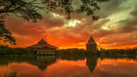 Sunset over the University of Indonesia campus showcasing traditional architecture reflected on calm water, captured in an HD man-made desktop wallpaper.