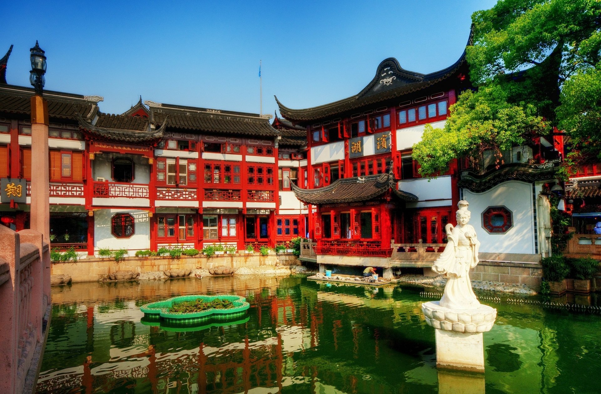 2K Quad HD PC wallpaper: Shanghai Tea Palace, a man-made red palace complex beside a reflective pond with stone statue and green trees under a clear blue sky.