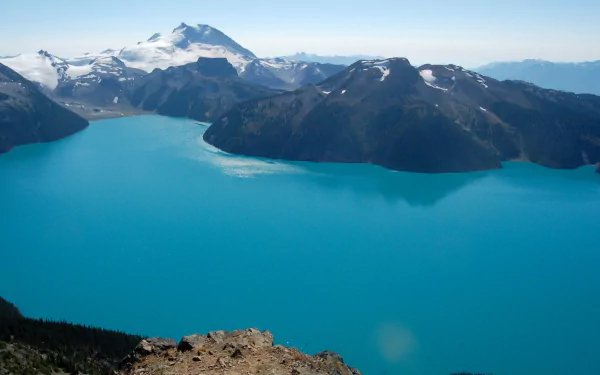 HD desktop wallpaper featuring the serene turquoise waters of Garibaldi Lake surrounded by snow-capped mountains under a clear blue sky.
