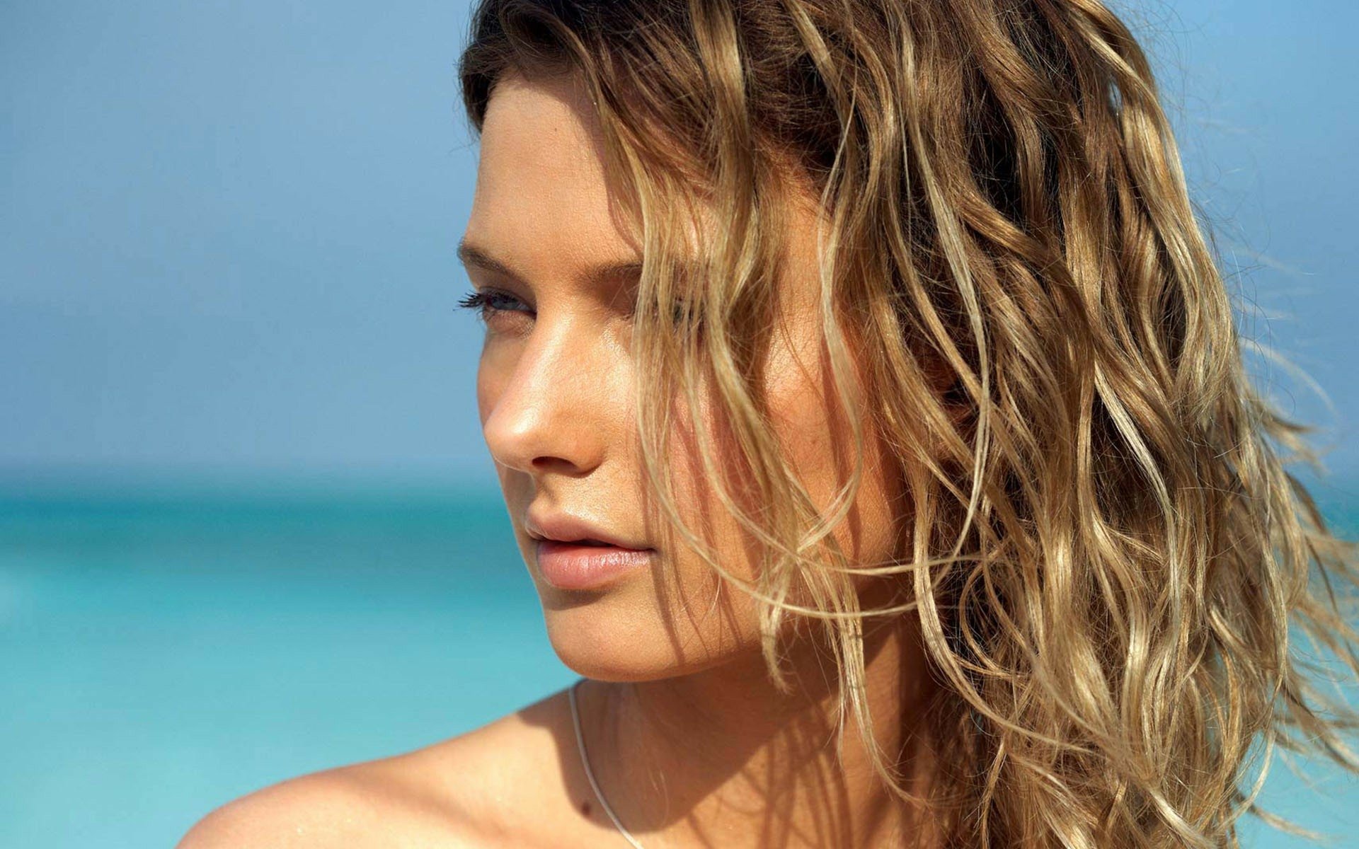 Close-up of a woman's face with wet, wavy blonde hair against a turquoise ocean — HD PC desktop wallpaper and background.