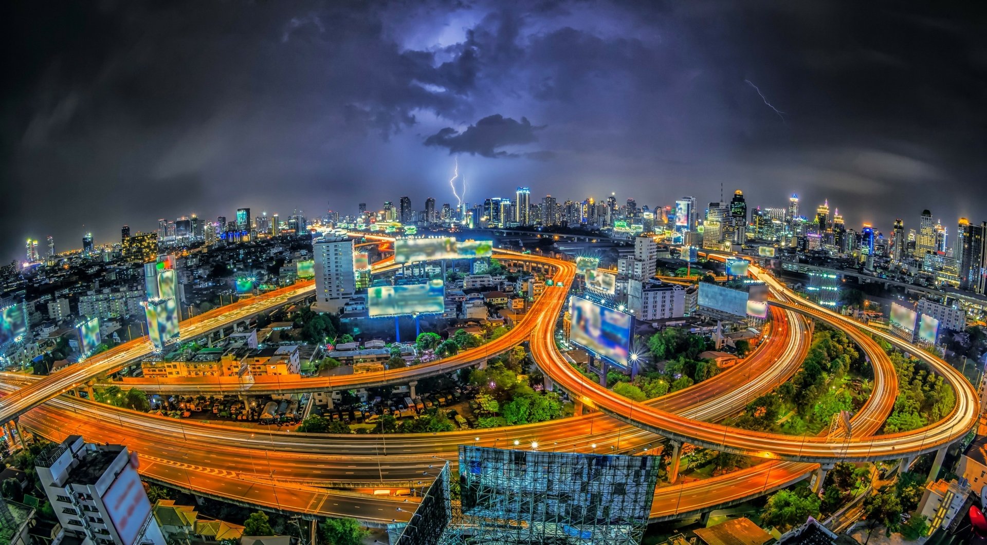 2K Quad HD desktop wallpaper of Bangkok, Thailand: a man-made night cityscape with glowing highways and skyscrapers beneath dramatic clouds.
