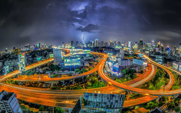2K Quad HD desktop wallpaper of Bangkok, Thailand: a man-made night cityscape with glowing highways and skyscrapers beneath dramatic clouds.