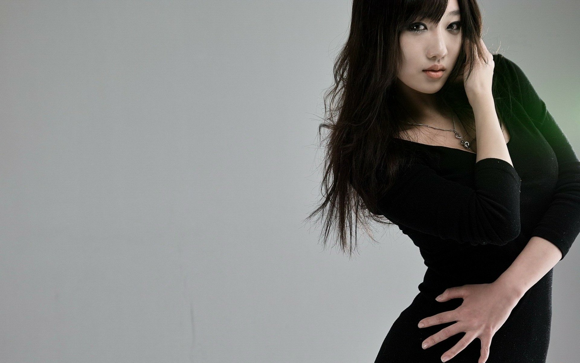 A stylish Asian woman poses elegantly in a black outfit against a simple gray background, creating a striking HD desktop wallpaper and background image.