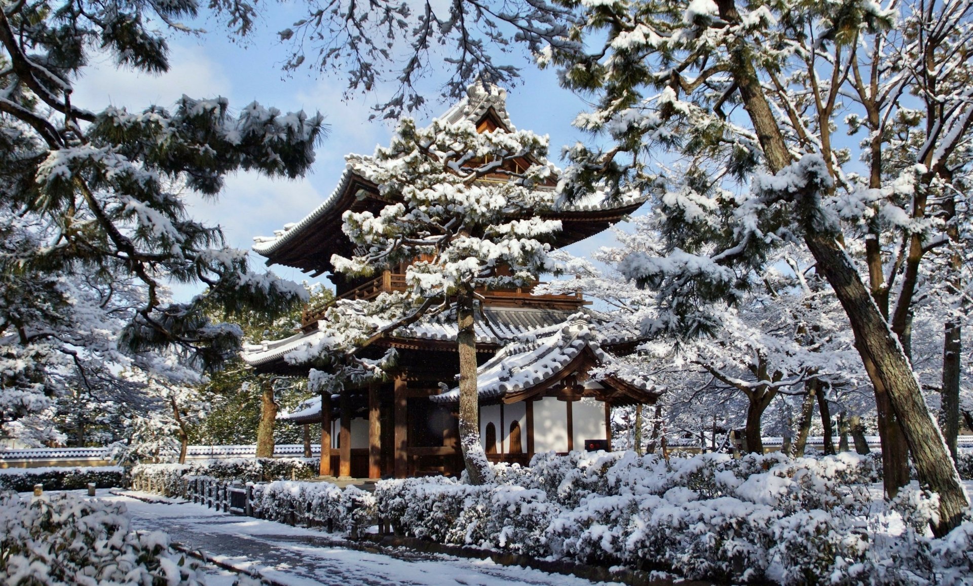 Snow-covered Kennin-ji Temple in Kyoto during winter, surrounded by trees and traditional architecture, captured in HD as a serene desktop wallpaper.