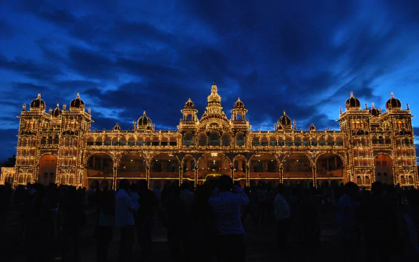 A stunning view of Mysore Palace in Karnataka, India, depicted at night with vibrant lighting against a dramatic sky, showcasing its magnificent architecture.
