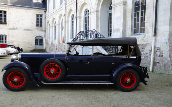 HD PC desktop wallpaper/background: side view of a vintage vehicle — a dark blue Lagonda 16/80 with red wire wheels parked in front of a classical stone building.