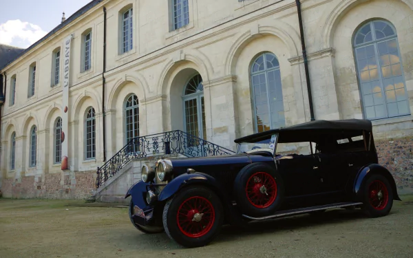 A classic Lagonda 16/80 vehicle parked in front of a historic building, captured in high definition for a PC desktop wallpaper and background.