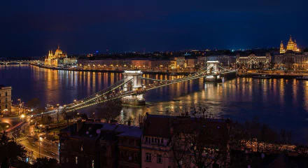 A stunning night view of the Chain Bridge over the Danube in Budapest, showcasing the illuminated architecture and vibrant reflections on the water. A captivating desktop wallpaper choice.