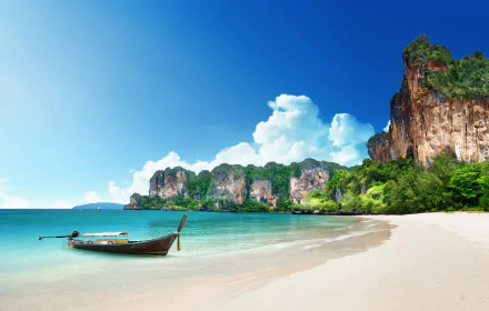 A tranquil tropical beach in Thailand, featuring a serene coastline, lush cliffs, a clear blue ocean, and a traditional boat resting on soft sand, capturing the essence of paradise.