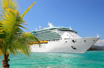 A large cruise ship anchored in vibrant turquoise water, framed by palm trees, creating a serene tropical scene. This HD image serves as a stunning desktop wallpaper.