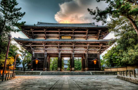 HD desktop wallpaper of Tōdai-ji’s grand wooden gate, showcasing its religious architecture framed by trees under a dramatic sky.