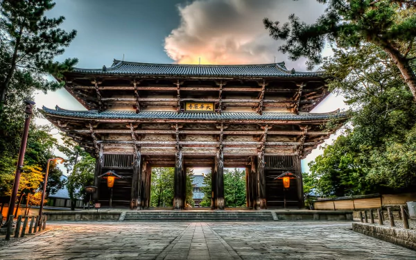 HD desktop wallpaper of Tōdai-ji’s grand wooden gate, showcasing its religious architecture framed by trees under a dramatic sky.