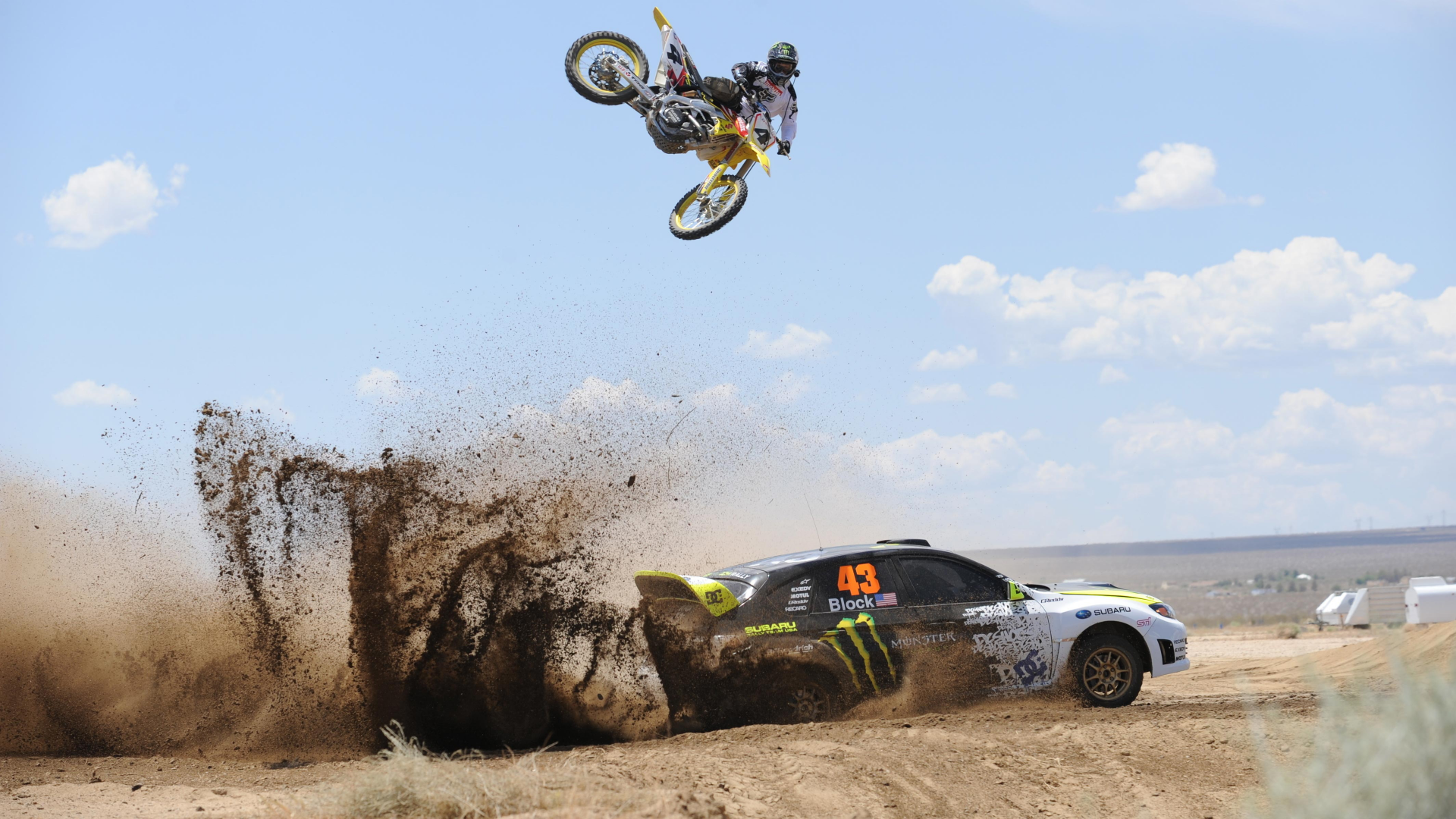 4K Ultra HD PC desktop wallpaper background: high-octane racing sports scene — rally car throws dirt as a motocross rider soars overhead.